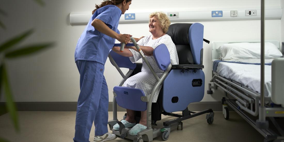 Patient in chair using standing aid